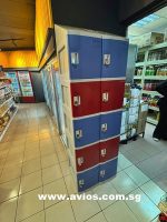 Colorful storage lockers inside a convenience store with shelves and refrigerators in the background.